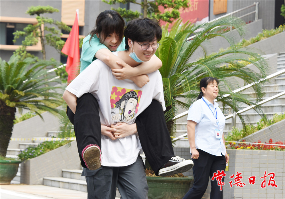 6月8日，普通高等学校招生全国统一考试湖南省澧县第二中学考点，一名男考生背着脚部受伤的女考生走向考场。             柏依朴  何祖华 摄.jpg